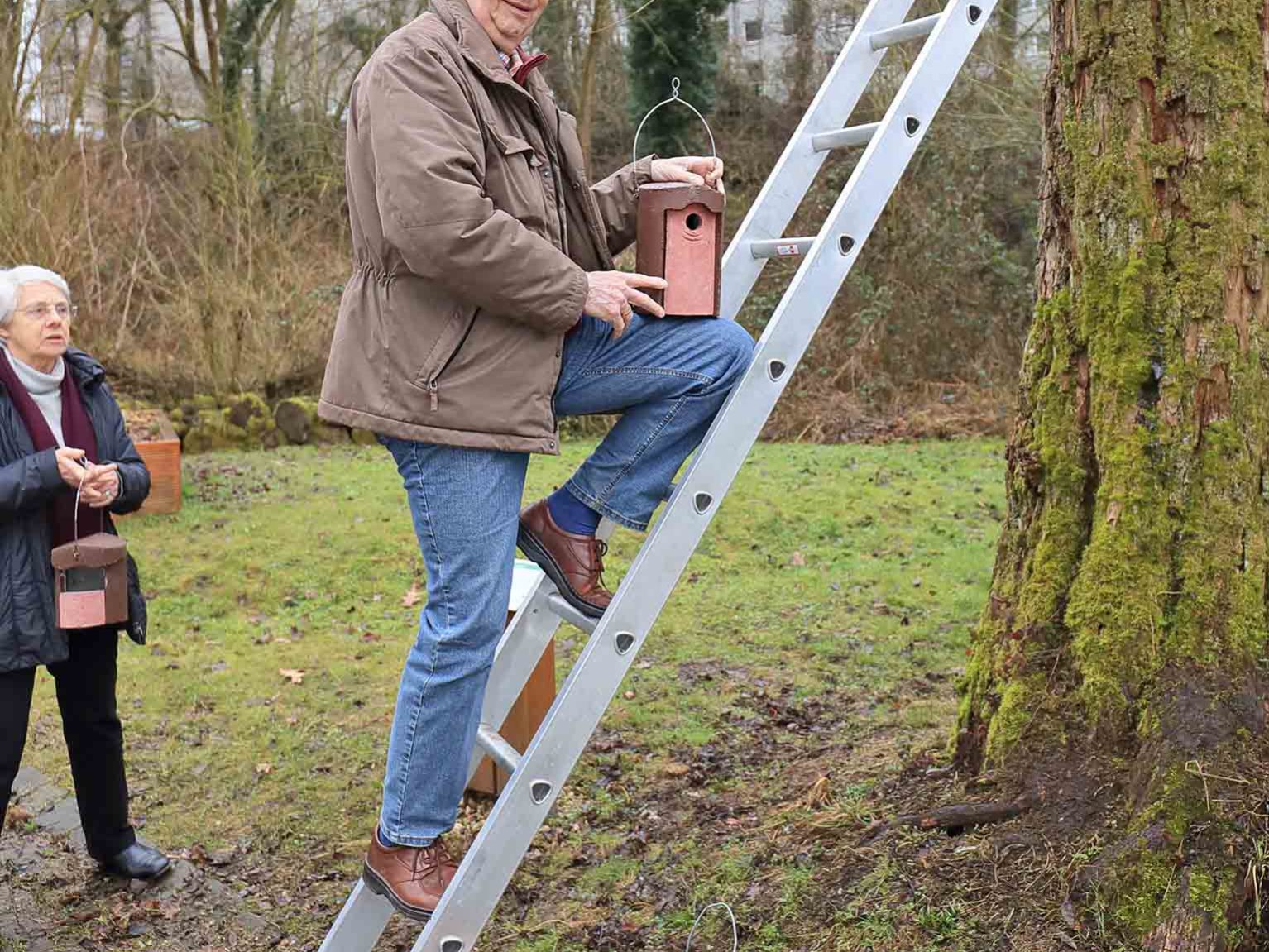Erich Schulz hängt einen Meisenkasten an einen Baum
